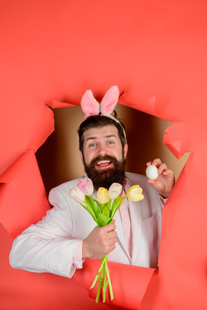 Happy bearded man holds basket with eggs and flowers. Easter basket. Spring holiday. Easter bunny...