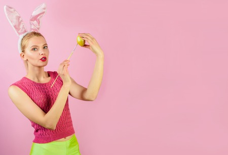 Rabbit woman with bunny ears painting easter egg. Sensual girl with rabbit ears painting Easter eggs. Cute lovely woman wearing bunny ears on Easter day. Happy moments and Easter celebration concept.の写真素材