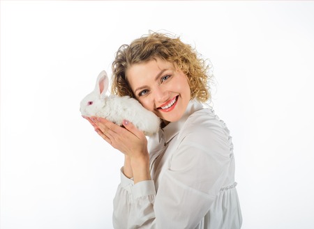 Smiling woman hugs baby rabbit. Happy woman with white baby rabbit. Girl holds cute little bunny. Friendship with Easter Bunny. Woman holds fluffy rabbit. Style of Easter bunny. Cute rabbit friend petの写真素材