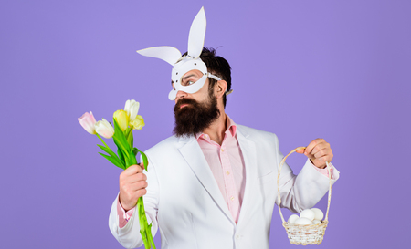 Happy Easter! Easter day. Spring holidays. Egg hunt. Easter bunny costume. Easter concept. Bearded man in bunny mask holds eggs. Man in bunny mask. Rabbit man. Flowers bouquet. Man with tulips. Springの写真素材