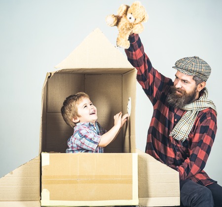 Happy family play with cardboard rocket. Cosmonaut concept. Cute boy playing with rocket and teddy...