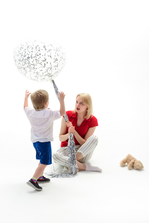 Blonde woman and little boy with big balloon. Big white balloon. Mother holds flying balloon. Mother day. Celebration concept. Advertising concept. Birthday party. Isolated on white background.の写真素材