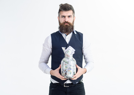 Bearded man with cash money in jar. Business success, banking concept. Business man hold jar full of money banknotes. Money savings, accounting concept. Banknotes. Dollars in glass jar.の写真素材