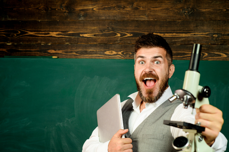 Education and learning concept. School. Learning is interesting. Positive teacher with laptop computer and microscope. Happy bearded professor is giving interesting lecture for students in classroom.の写真素材