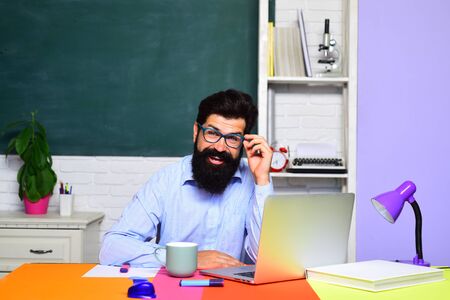Back to school. Smiling male teacher in class. Learning and education concept. Homework. Lessons. School subjects. University. High school. Preparing for exam. Online test.の写真素材