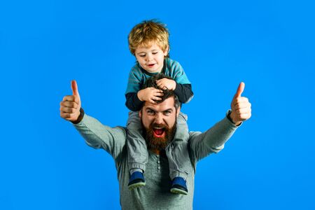 Happy father's day. Parent shows thumb up carries son on shoulders. Happy cute boy piggybacking on...