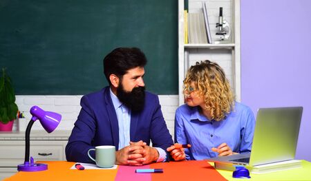 Students and tutoring education concept. Portrait of couple university students. Exam in college. Young male teacher with female student over green chalkboard background. Teachers couple in classroom.の写真素材