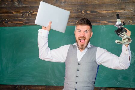 Educational process. Screaming tutor with laptop and microscope. Docent in chemistry or biology...