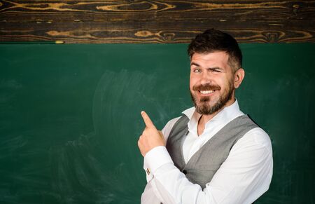 Back to school. Student in classroom near blackboard pointing at copy space. Male teacher in classroom. Teacher giving lesson to student. Education, high school, people concept. Student at auditorium.の写真素材