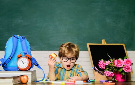 Tasty food. Small boy have school lunch in classroom. Little boy eat apple at lunch break. Young...
