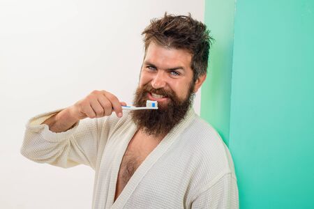 Dental higiene. Bearded man brushing teeth with toothbrush. Oral care. Smiling young man with toothbrush cleaning teeth. Morning routine of washing teeth. Handsome man cleaning teeth in bathroom.の写真素材