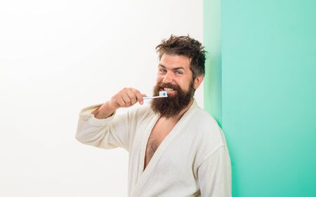 Handsome man cleaning teeth in bathroom. Oral care. Bearded man brushing teeth with toothbrush. Dental hygiene. Smiling young man with toothbrush cleaning teeth. Morning routine of washing teeth.の写真素材