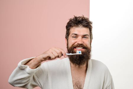 Morning treatments. Morning routine. Smiling bearded man brushing teeth. Tooth brush. Tooth paste. Health care. Dental hygiene.の写真素材