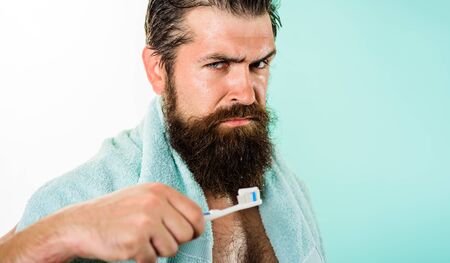 Oral care. Man brushing teeth with toothbrush. Dental hygiene. Healthcare. Handsome man cleaning teeth in bathroom. Serious man with toothbrush cleaning teeth. Morning routine. Washing teeth. Closeup.の写真素材