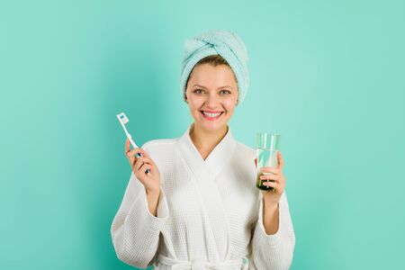 Oral care. Smiling girl brushing teeth with toothbrush. Dental hygiene. Happy young woman with toothbrush cleaning teeth. Attractive woman cleaning teeth in bathroom. Morning routine of washing teeth.の写真素材