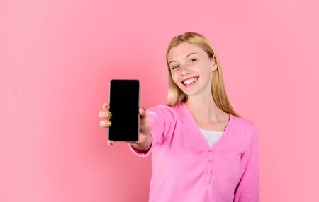 Young beautiful woman holds smartphone with empty screen. Smile girl holds mobile phone. Black Friday, cyber Monday.の写真素材