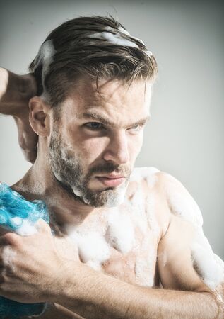 Sexy man with naked body washing with sponge. Muscular man in shower.の写真素材