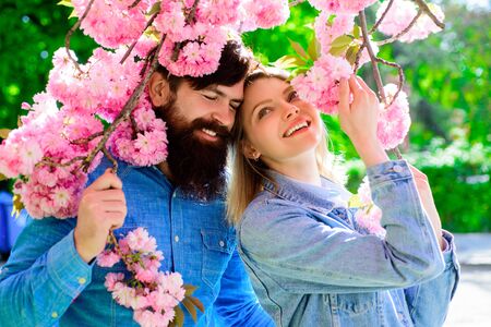 Man and woman in blooming garden. Couple stand near sakura tree. Couple spend time in spring garden....