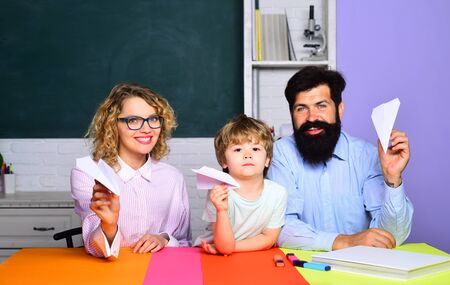 Little boy and his parents with paper airplane. Origami lesson. Education concept. Happy family. Education for kids out of school. Mother father and son together schooling. Boy from elementary school.の写真素材
