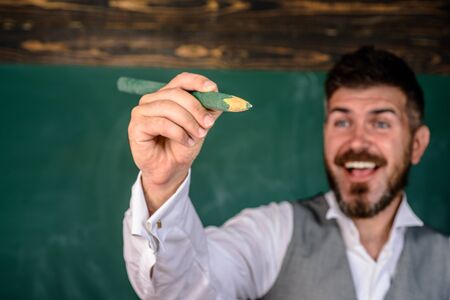 Back to school. School equipment. School supplies. Happy educator, teacher with pencil in hand. Educational or academic concept. University student writing with big pencil. Selective focus on pencil.の写真素材