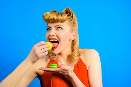 Happy woman with delicacy macaroons. Girl eat tasty macaroon cookies. Cooking, confectionery, food and baking concept. Traditional french macaroons. Sweet meringue-based confection. Pastry macaroon.の写真素材