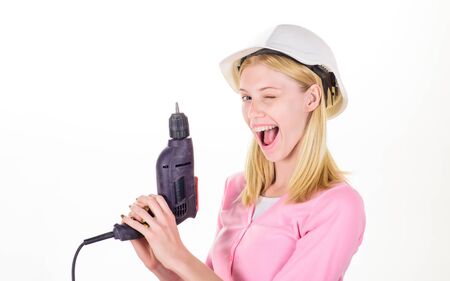 Woman with electric screwdriver. Sexy builder girl in hard hat or helmet holds electric screwdriver. Winking woman with drill. Female contractor with hand power drill. Hammer drill or screwdriver. DIYの写真素材