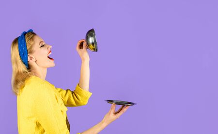 Smiling woman holds food tray in restaurant. Happy woman with restaraunt cloche. Retro woman holds empty metal tray with lid. Pinup girl with metallic dish. Presentation&restaurant serving. Copy spaceの写真素材