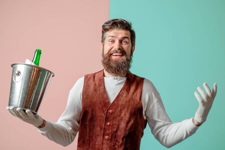 Smiling sommelier hold bucket with bottle of wine. Italian style. Isolated. Alcohol. Waiter holds...
