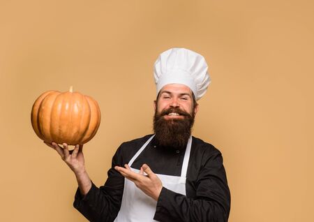 Organic food. Happy halloween. Healthy product. Harvest festival. Thanksgiving day cooking or autumn recipes concept. Chef man with pumpkin. Male chef in uniform with pumpkin. Bearded man hold squashの写真素材