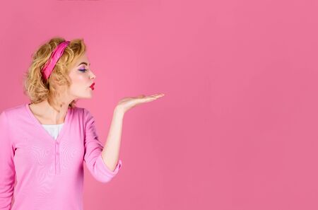 Skincare, hair care, beauty concept. Pin ap girl blowing kiss from hand. Woman with perfect skin, red lips. Beautiful girl showing empty copy space on open hand palm for text. Copy space for advertise.の写真素材