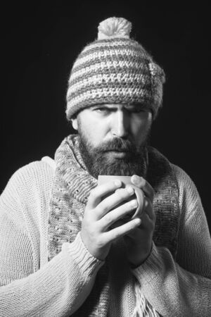 Bearded man warming up with hot tea. Man warming up with hot tea in cold autumn, winter time. Bearded man drinks hot beverage. Cold time - warm drinks. Man in sweater enjoying cup aromatic coffee/tea.の写真素材