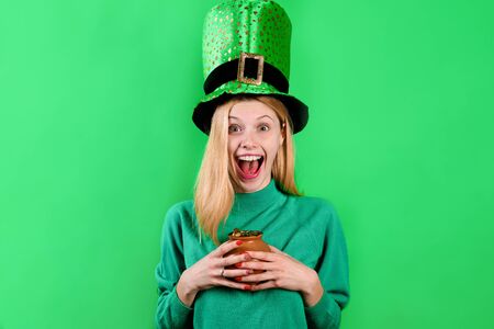 Patrick's Day. Happy girl in green top hat holds pot with gold. Saint Patrick's Day. Leprechaun. Irish Traditions. Green hat with clover. Clover. Pot with gold. Gold. Green top hat.の写真素材