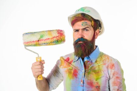 Painter. Bearded painter holds paint roller. Painter with painting roller. Room painting job. Repair. Hard hat. Man worker. Construction. Industrial concept. Repair paintng tool.の写真素材