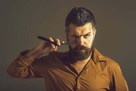 Male hairstylist barber. Barbershop man. Confident look. Skincare, beauty, shaving. Straight razor, barbershop, barber accessories. Man in barbershop. Bearded macho shaving with straight razor blade.の写真素材