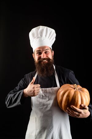 Autumn recipes concept. Happy halloween. Thanksgiving day cooking. Useful vegetables. Autumn crop. Seasonal vitamin. Happy chef man with beard holds pumpkin. Bearded man cook in chef hat with pumpkinの写真素材