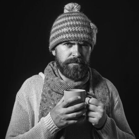 Business man drinking coffee in cafe. Relaxed man drinking tea. Young guy in winter clothes enjoy hot drink. Bearded man drinks tea in cold winter. Winter season. Man with beard with cup of coffee/teaの写真素材