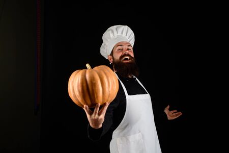 Useful vegetables. Autumn crop. Seasonal vitamin. Happy chef man with beard holds pumpkin. Thanksgiving day cooking. Autumn recipes concept. Bearded man cook in chef hat with pumpkin. Happy halloweenの写真素材