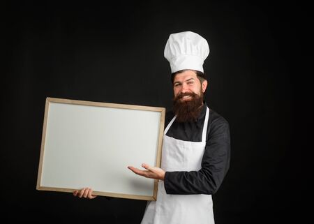 Empty menu chalkboard with copy space for text. Chef menu. Professional chef on kitchen. Master chef, baker or cook shows menu sign blackboard. Cooking, culinary, diet, advertisement and food conceptの写真素材