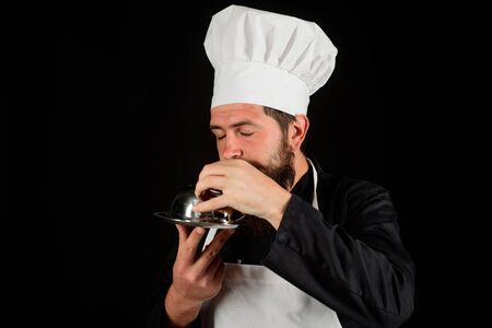 Waiter. Chef man in uniform with cloche food. Cook hold metal tray with lid. Servant carry metallic cloche. Waiter holds metal tray with lid. Professional chef holds dish. Chef presenting silver trayの写真素材