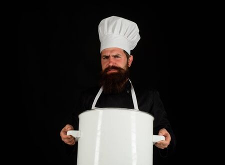 Male chef holds pot. Chef, cook or baker with saucepan in hand. Professional chef in uniform and hat holds pan. Cooking, food, profession concept. Chef in uniform cooking with cooking pot. Casseroleの写真素材