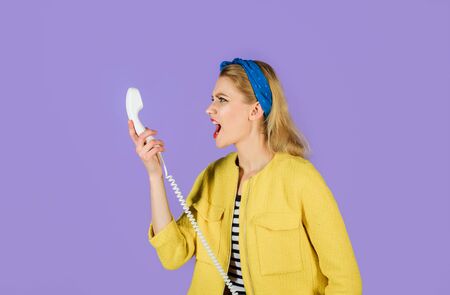 Human emotion. Angry pinup girl screaming in handset. Screaming woman with handset of stationary...