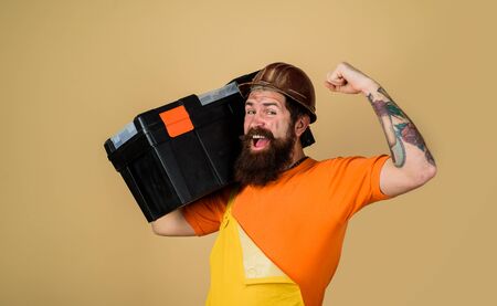 Tools for repair. Repair. Handyman concept. Repairman in overall hold toolbox. Repair kit. Happy builder man in workwear carries tool box. Man with tool box. Builder in protective helmet with toolboxの写真素材