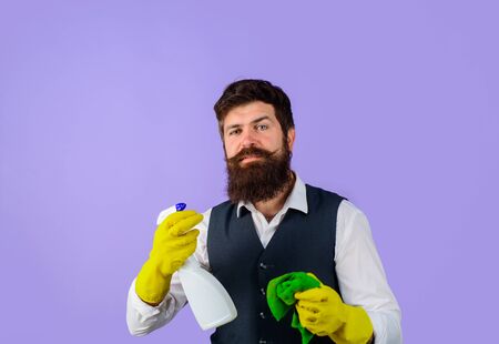 Male janitor with cleaning equipments. Professional cleaning man in uniform. Bearded man in uniform, rubber gloves with cleaning products. Domestic service cleaner man with rag and cleaner sprayの写真素材