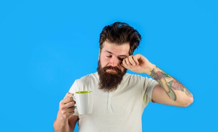 Morning refreshment and drink. Tired sleepy man with beverage in cup. Refreshment and energy. Bearded man with white coffee cup. Handsome bearded young man drinking coffee or tea. Breakfast conceptの写真素材