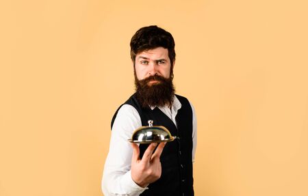 Waiter holds metal tray with lid. Professional waiter in uniform. Serious butler with serving tray....