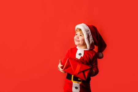 Christmas children. Little kids celebrating Christmas. Child with Christmas present. Happy child in Santa costume. Little Santa Claus gifting gift. Cute boy in santa hat. New year kid. Happy new yearの写真素材