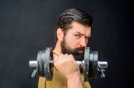 Fitness. Strong man training with dumbbells. Bearded man exercise with dumbbell. Handsome athlete man with dumbbells. Muscular sportsman with dumbbells training at gym. Sportsman making weightliftingの写真素材