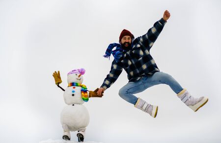 Bearded man playing with snowman. Santa claus man with snowman in winter hat. Man with snowman....