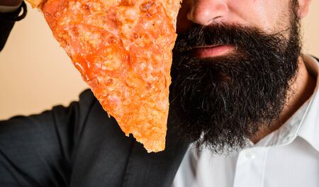 Bearded man eating slice of pizza. Bearded man eating pizza. Man eating hot fresh pizza slice. Delicious fast food meal. Italian cuisine concept. Tasty pizza at restaurant. Lunch or dinner. Closeupの写真素材