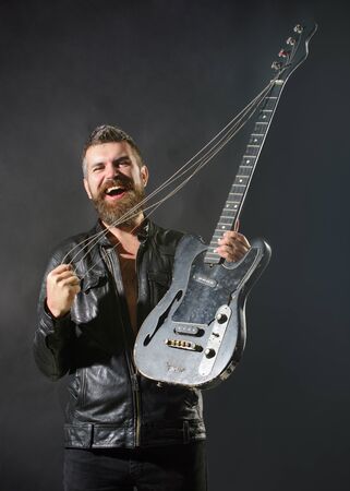Music. Concert. Entertainment. Musical instrument. Handsome rock star in leather jacket holds...